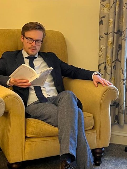 Jack Thomson reading in an armchair